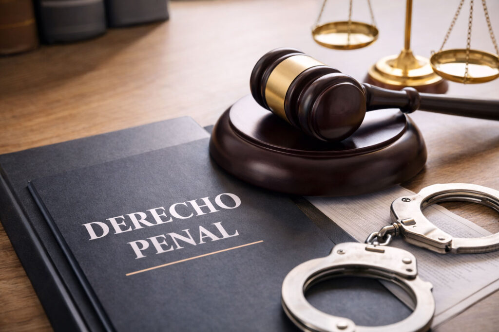 Símbolos del derecho penal con mazo judicial y esposas sobre escritorio de abogado